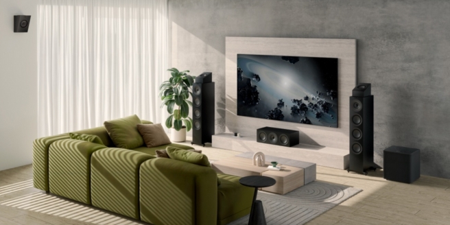 Stilvolles Heimkino mit grünem Sofa, großem Fernseher und Surround-Sound-Lautsprechern in einem hellen, modernen Wohnzimmer.