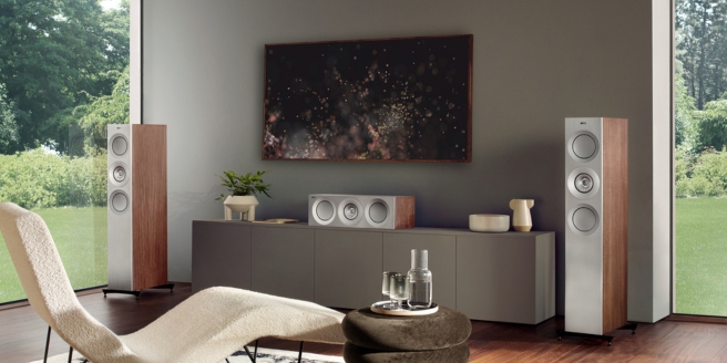 Salon moderne avec enceintes colonnes KEF en finition noyer, enceinte centrale assortie et mobilier élégant, avec baies vitrées et décoration minimaliste.