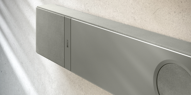 Close-up of a sleek, wall-mounted KEF speaker in a minimalist setting.