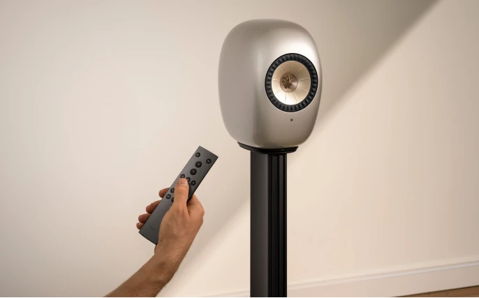 Blue Muo Bluetooth speaker hanging from carrying strap in bathroom is being controlled via phone.
