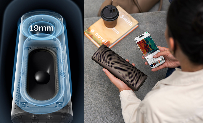 Persoon die een smartphone koppelt aan een Muo Bluetooth-luidspreker, met een koffiekopje en een boek in de buurt.