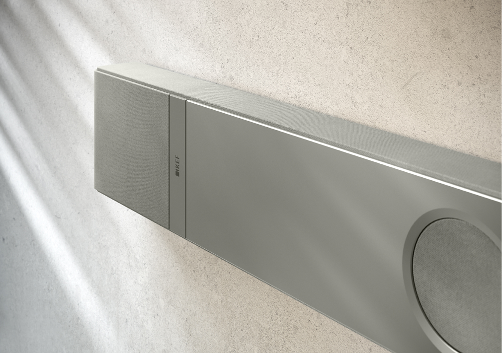 Close-up of a sleek, wall-mounted KEF speaker in a minimalist setting.