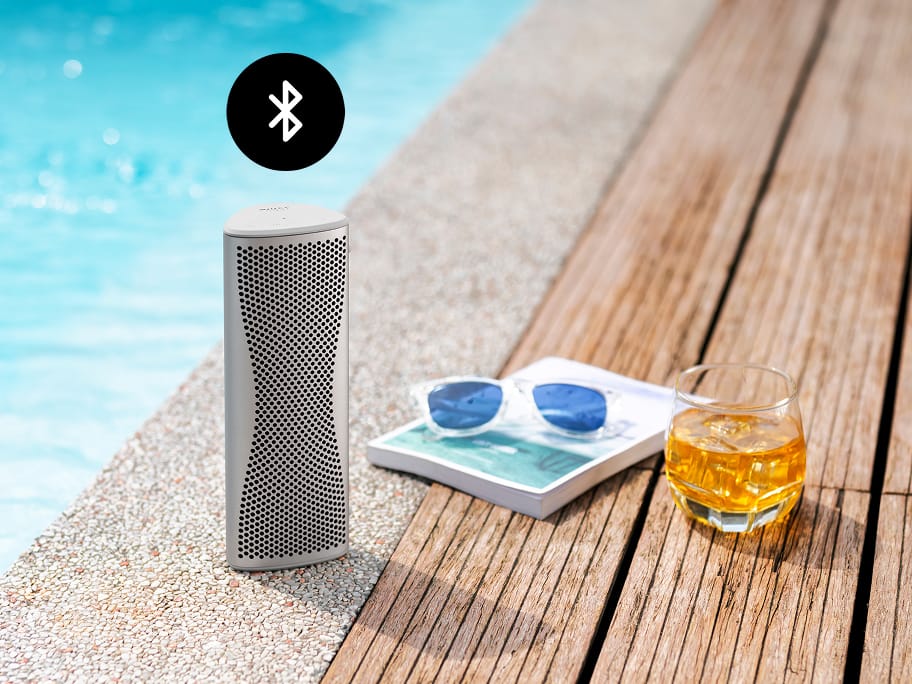 Enceinte Bluetooth Muo argentée à côté d’une piscine.