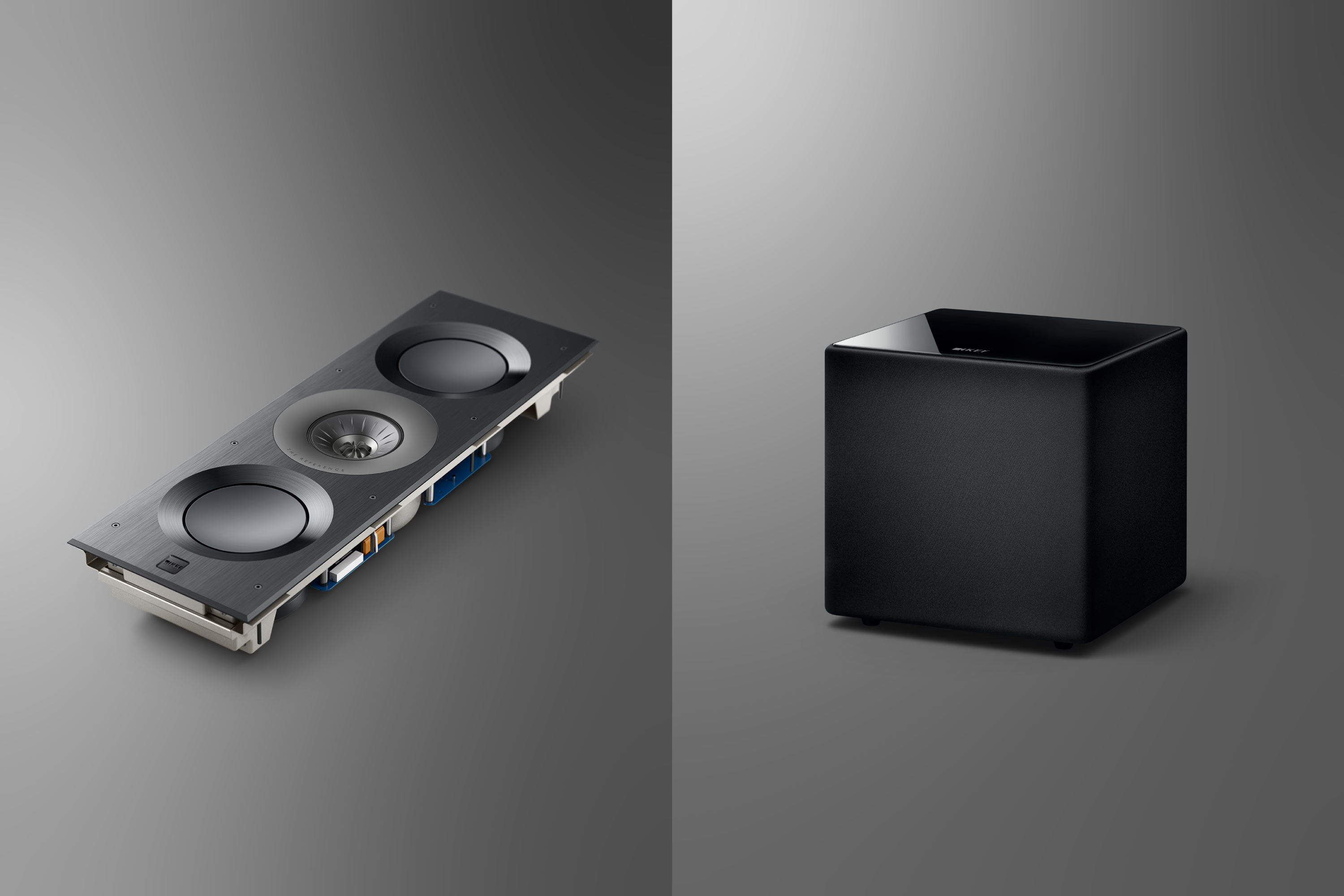 Detail of KEF's speakers with a black meth cloth grille and a mobile phone charging next to them