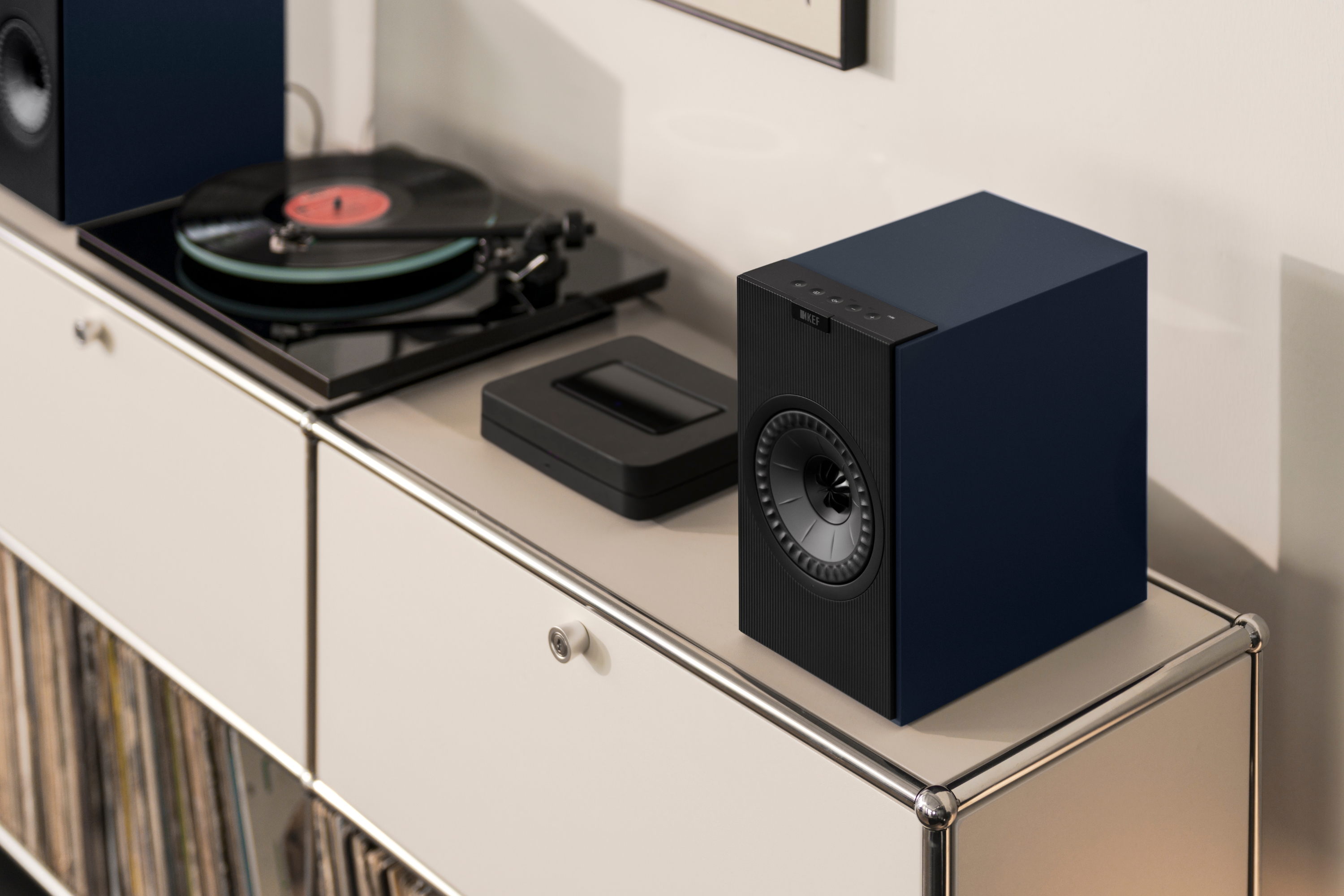 Draadloze KEF HiFi-speaker naast een platenspeler op een modern rek
