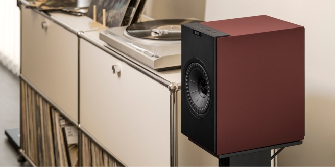 KEF kabelloser HiFi-Lautsprecher in roter Ausführung auf einem modernen Sideboard mit Plattenspieler