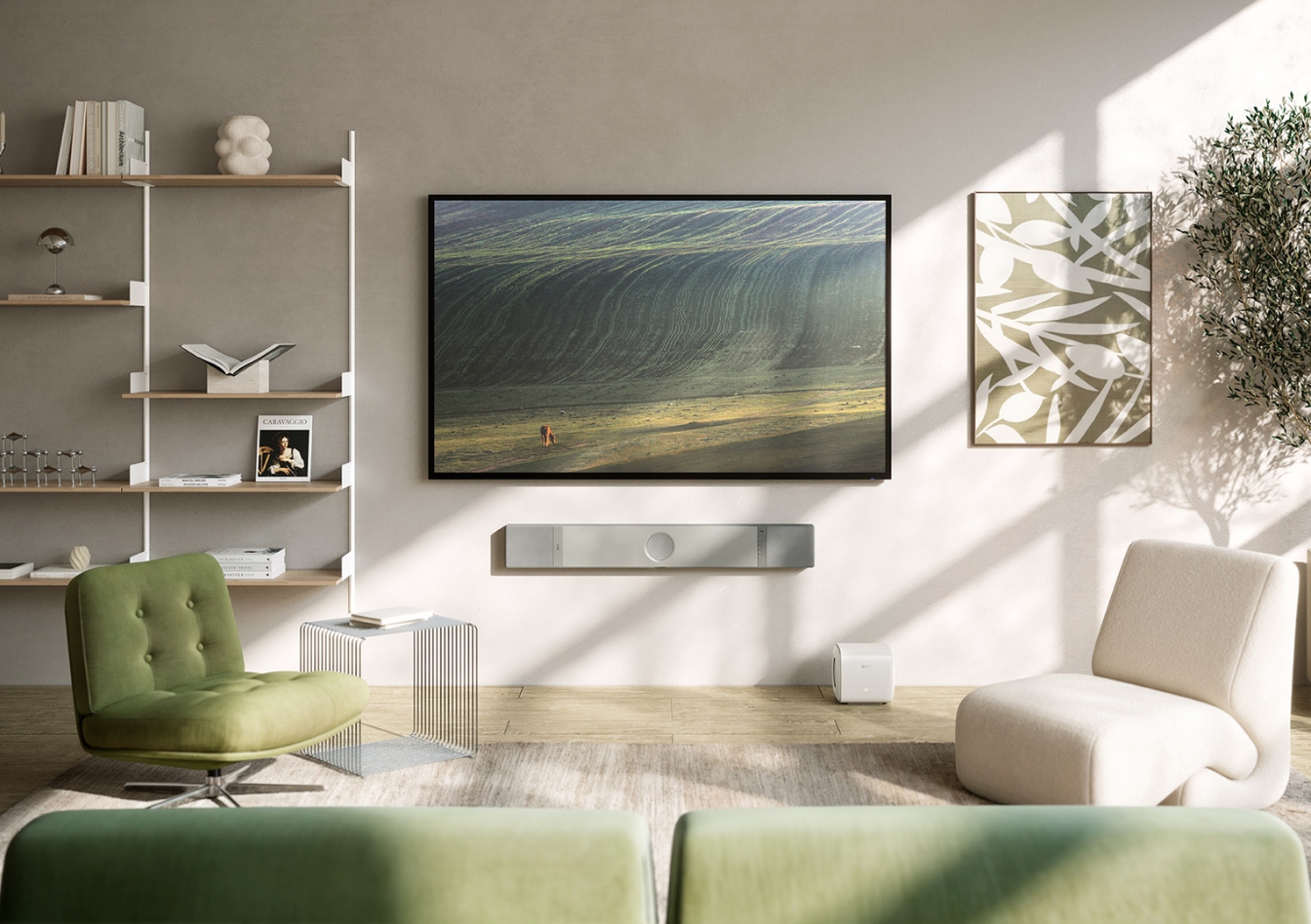 An der Wand montierte KEF Soundbar unter einem großen Flachbildfernseher in einem modernen Wohnzimmer mit neutraler Einrichtung und natürlichem Tageslicht.