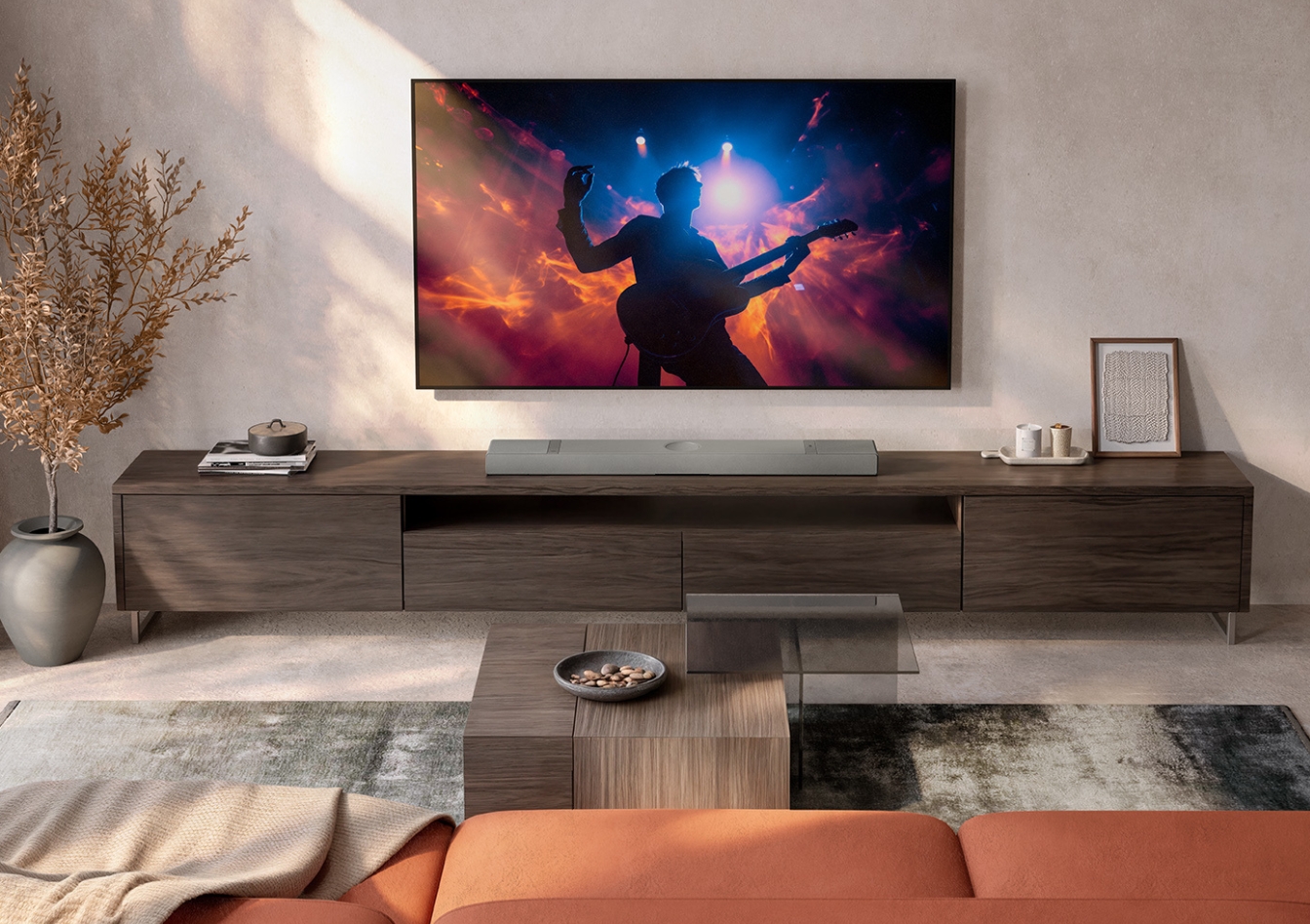 Moderne woonkamer met een aan de muur gemonteerde tv die een concertscène toont, donkerhouten tv-meubel, warme verlichting en minimalistische inrichting.