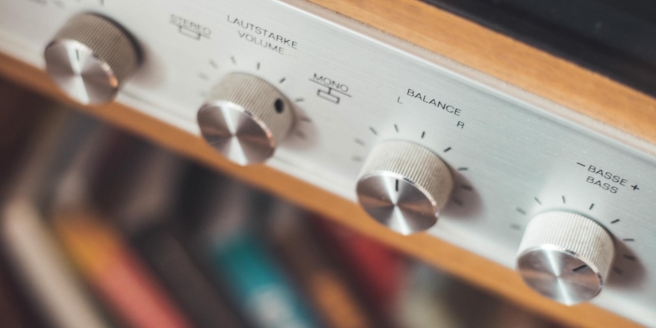 Close-up van een KEF hifi-versterker met een gedetailleerd beeld van de volumeknop en balanceregeling.