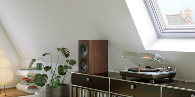 Moderne hifi-installatie met een platenspeler en KEF-boekenplankluidsprekers in een stijlvol interieur.