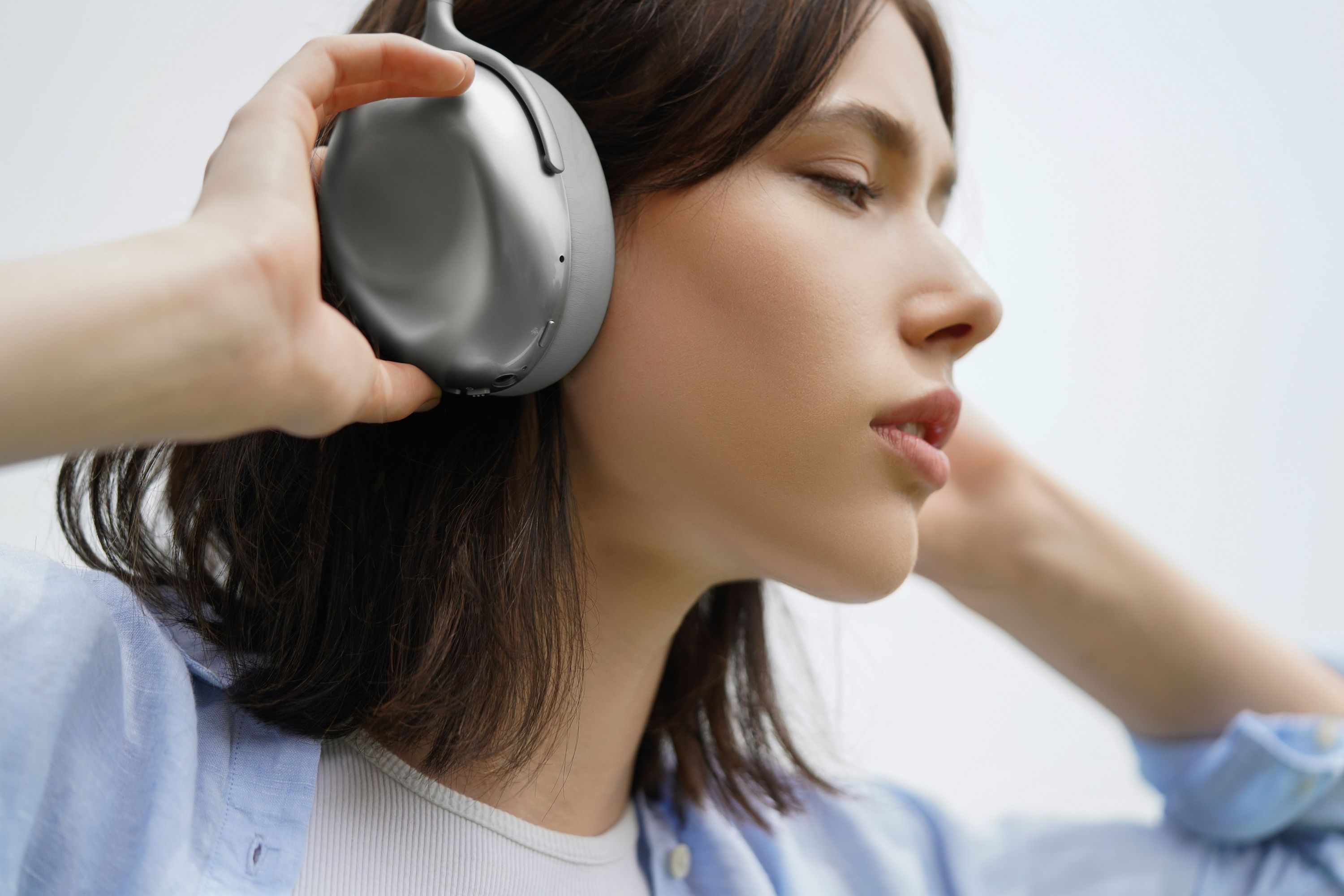 Female wearing a KEF silver Mu7 headphones 