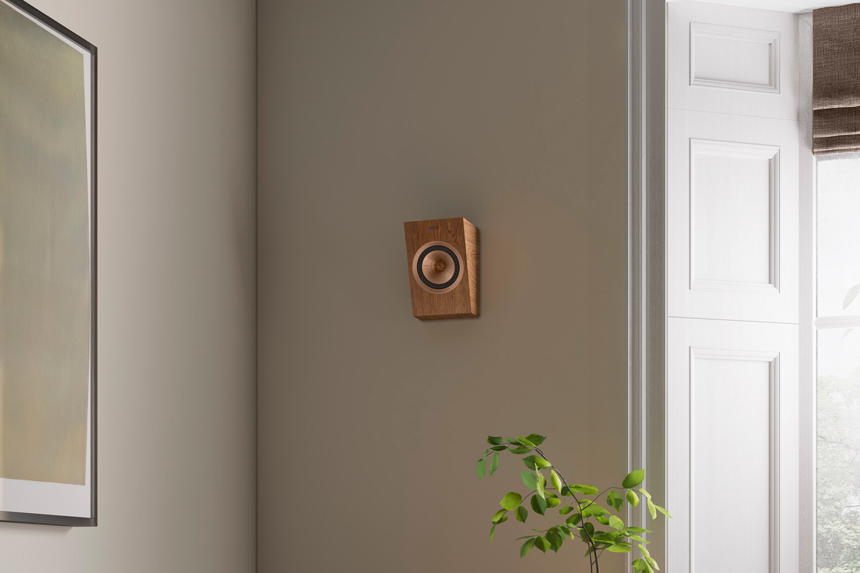 Compact KEF wall-mounted speaker in walnut finish installed in modern minimalist living room interior