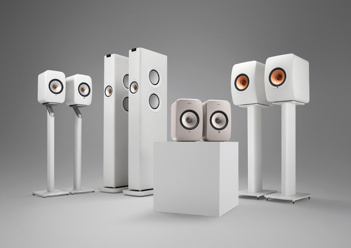 A collection of high-end bookshelf and floorstanding speakers displayed on stands against a grey background.