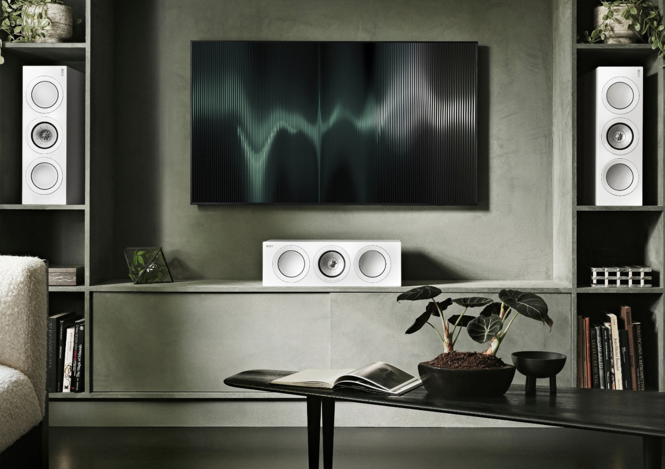 Modernes Wohnzimmer-Setup mit einem zentralen Flachbildfernseher, flankiert von KEF-Stereolautsprechern und einem passenden Center-Lautsprecher – veranschaulicht den Unterschied zwischen Mono- und Stereoklang