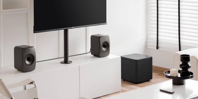 Kompakte KEF-Lautsprecher und ein Subwoofer in einem hellen, minimalistischen Raum – sie zeigen die optimale Lautsprecherplatzierung für ein Desktop- oder Media-Setup.