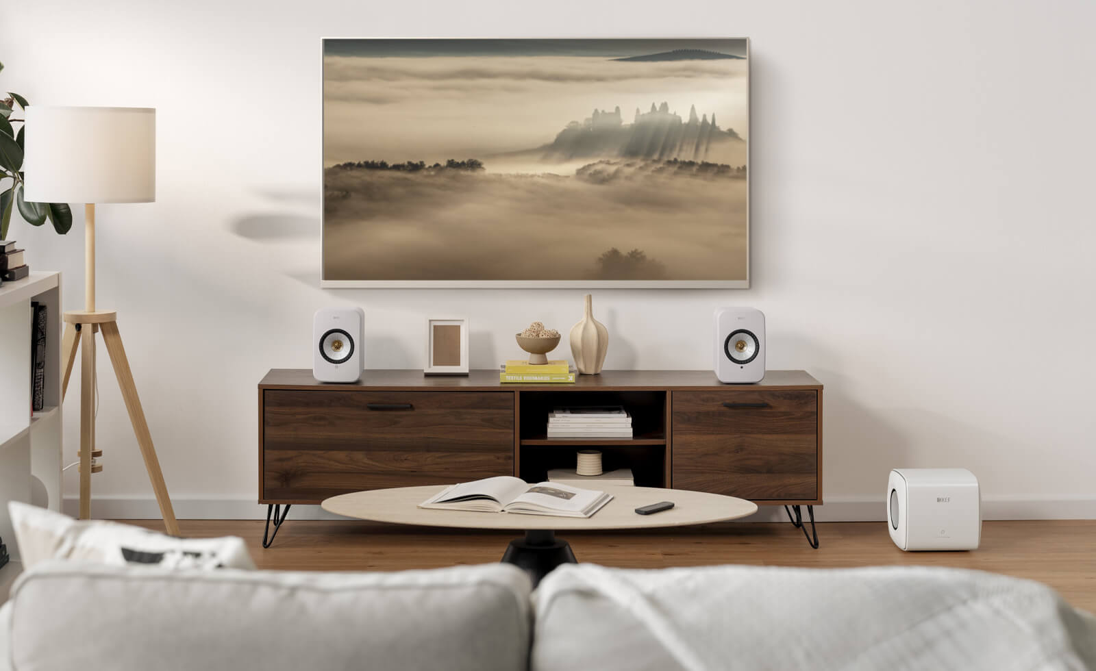 Lichte woonkamer met LSX II-luidsprekers die via een HDMI-kabel op de tv zijn aangesloten en een subwoofer op de grond.