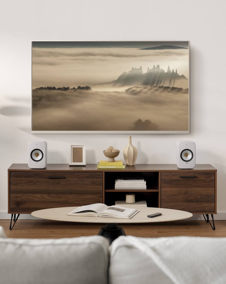 Lichte woonkamer met LSX II-luidsprekers die via een HDMI-kabel op de tv zijn aangesloten en een subwoofer op de grond.