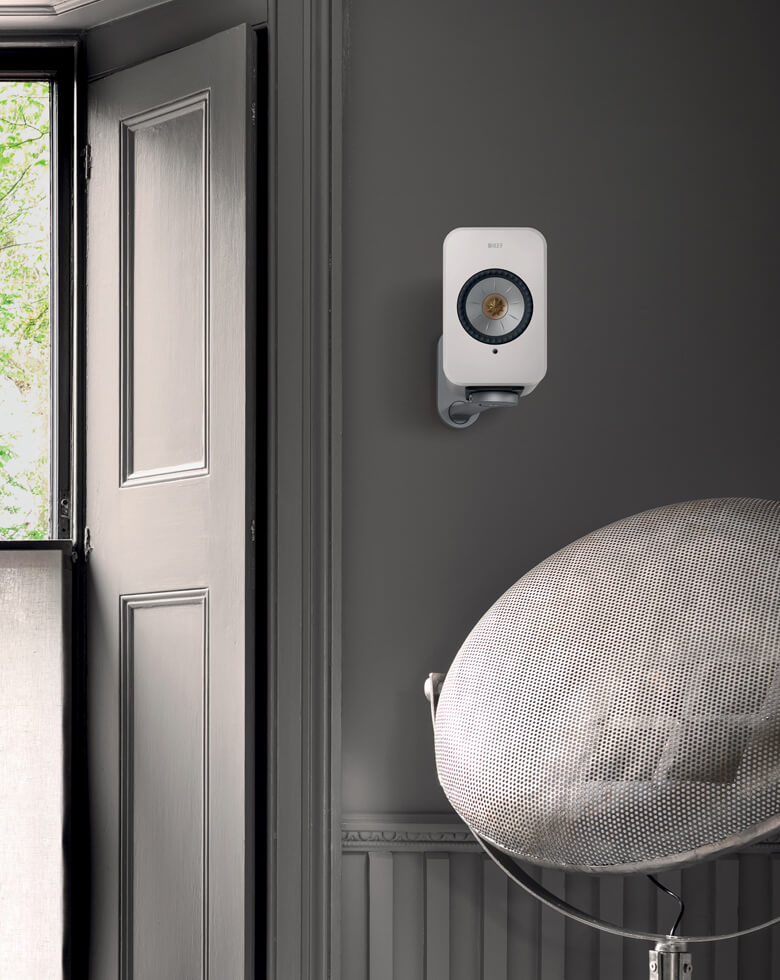 LSX II-luidspreker die in een woonkamer aan de muur hangt met B1-wandbeugels.