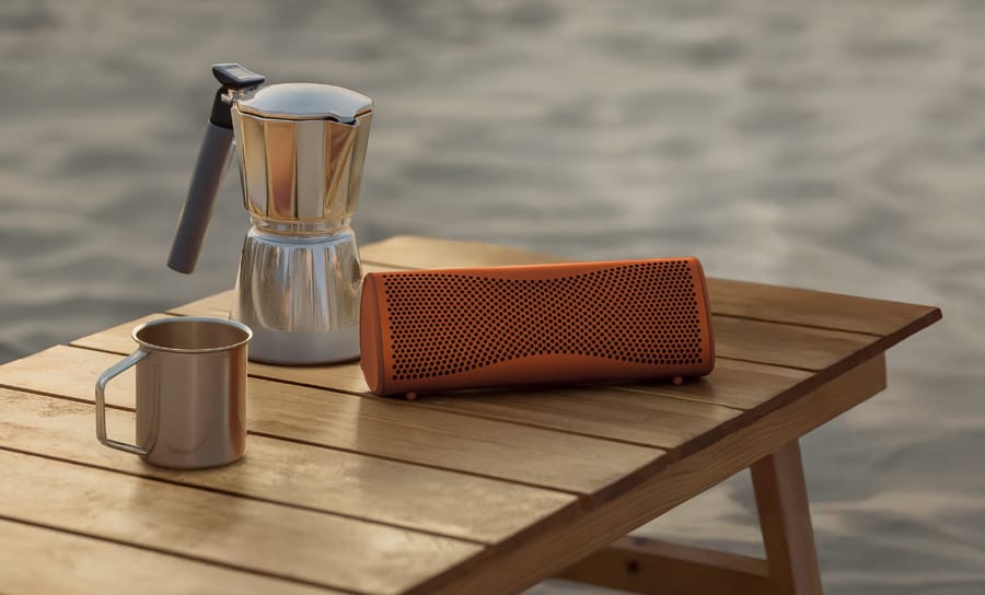 Enceinte portable Muo en orange à la plage.