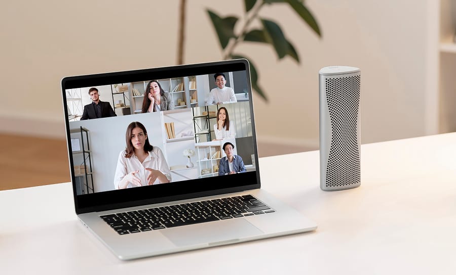 Enceinte Bluetooth Muo argentée utilisée pour une vidéoconférence sur un ordinateur portable.